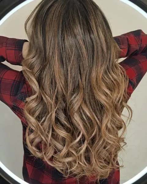 Pelo ondulado castaño con balayage en tonos avellana, visto de espaldas